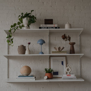 Wall shelf on white brick with decorative objects from Story & Teller