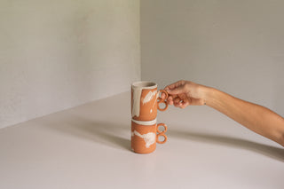Nichols Mugs in Terracotta Splatter Stacked with Hand Holding Handle